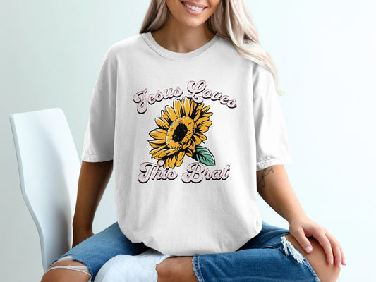 White t-shirt with "Jesus Loves This Brat" and a sunflower graphic.