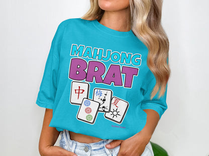 Blue t-shirt with "Mahjong Brat" in purple and pink, featuring four mahjong tiles.