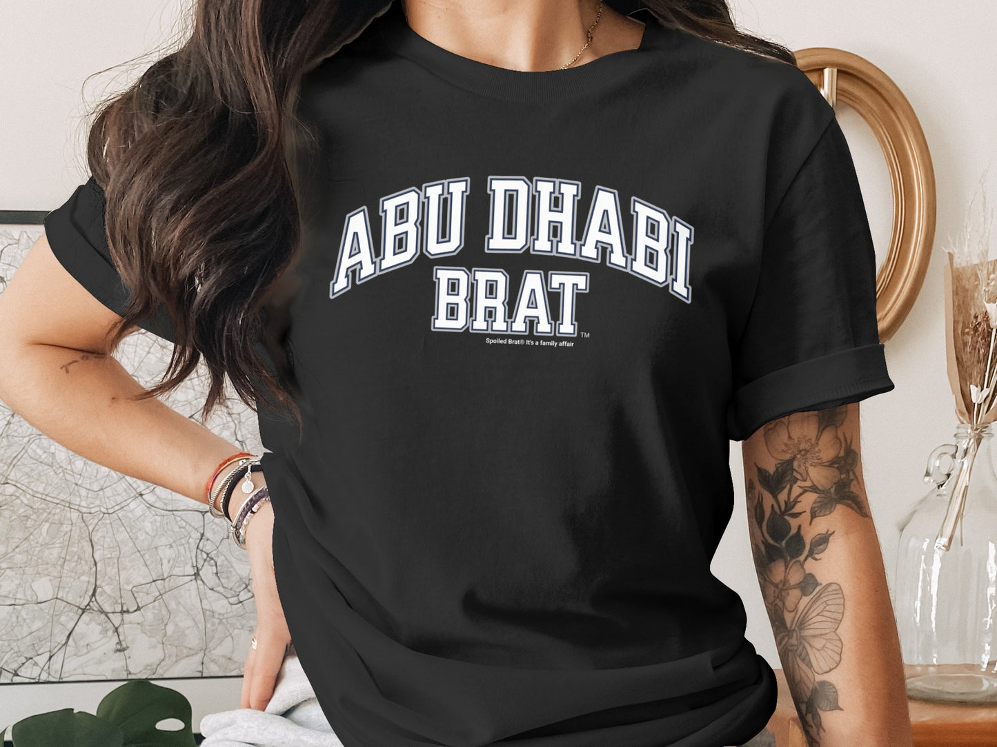 Black t-shirt with "ABU DHABI BRAT" and a small checkmark logo.