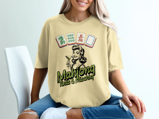 Woman wearing yellow t-shirt with "Mahjong This & Mischief" and mahjong tiles.
