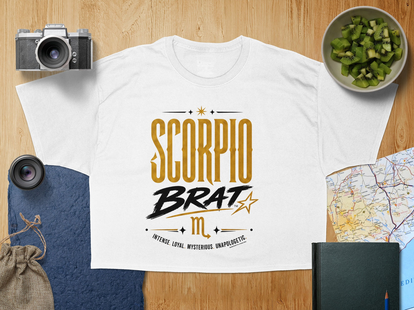 White t-shirt with "SCORPIO BRAT" graphic and Scorpio traits in gold and black.