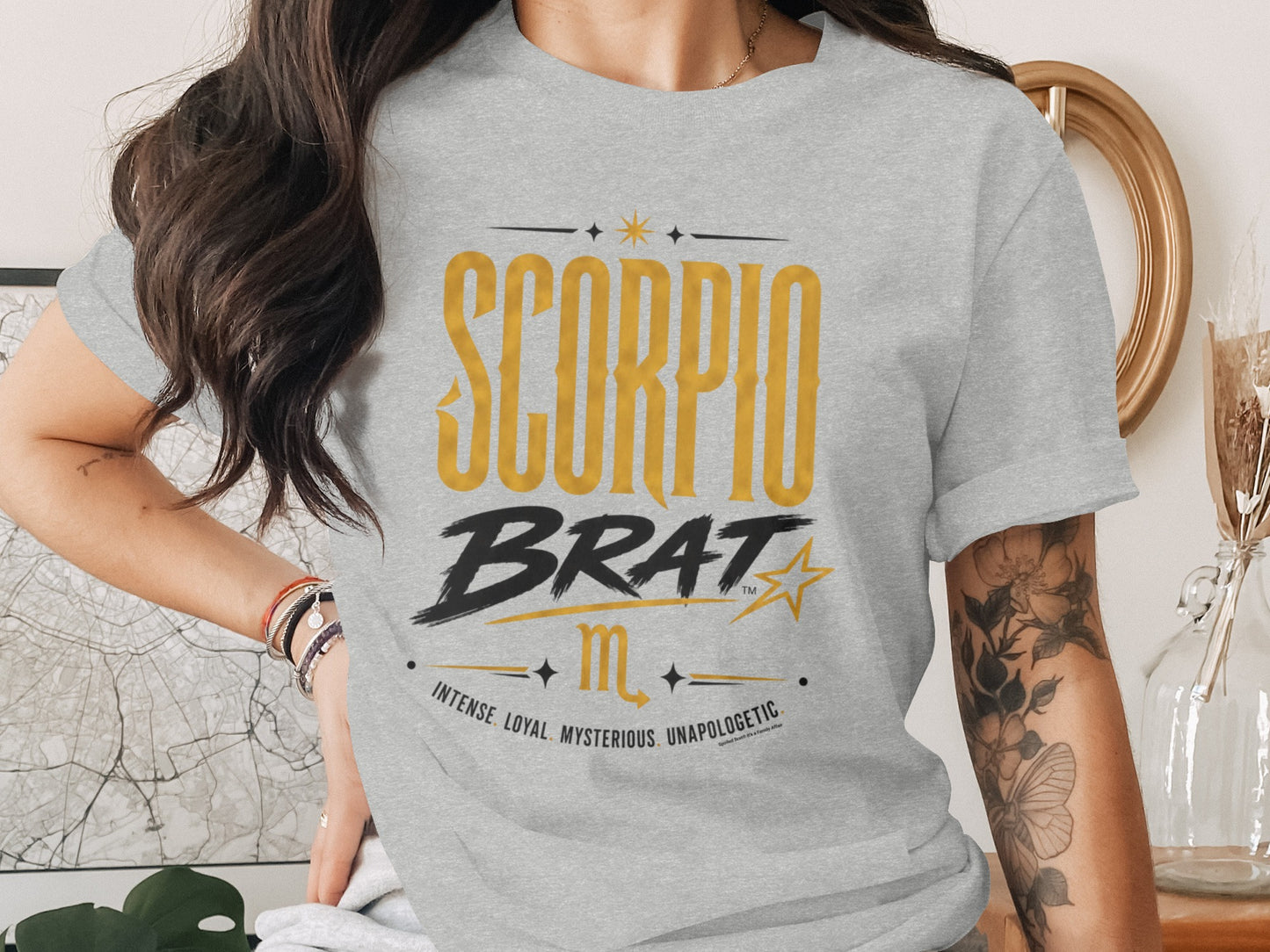Grey t-shirt with "SCORPIO BRAT" text and celestial accents.