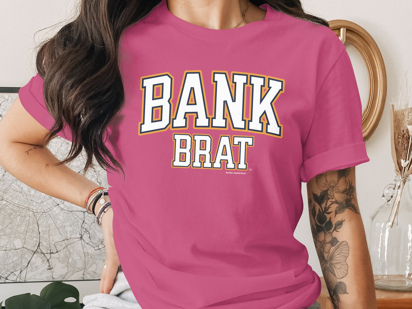 Pink t-shirt with "BANK BRAT" text graphic and small logo.