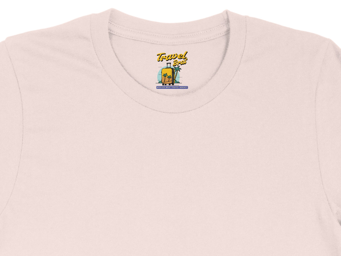 Pink t-shirt with "Travel Brat" suitcase and palm tree graphic; "Spoiled Brat Travel Agency" text.