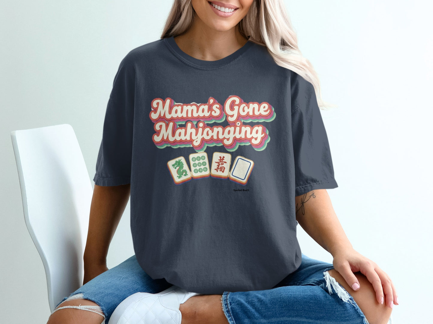 Dark t-shirt with "Mama's Gone Mahjonging" in colorful retro text and mahjong tiles.