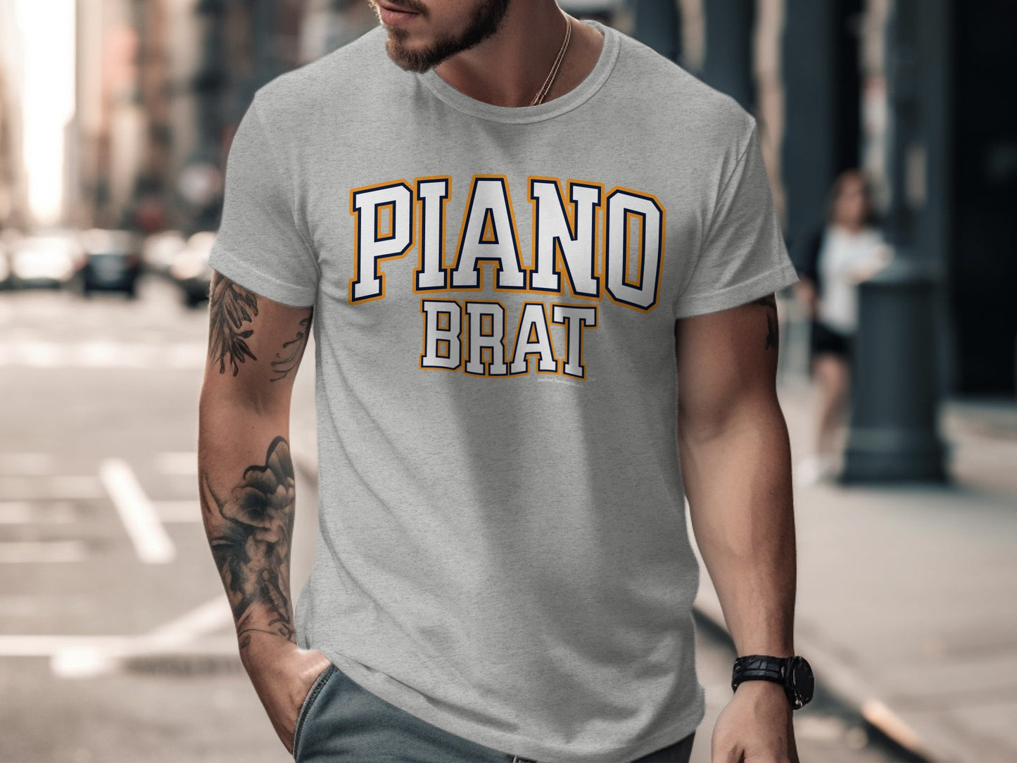 Grey t-shirt with "PIANO BRAT" text in white and orange collegiate font.
