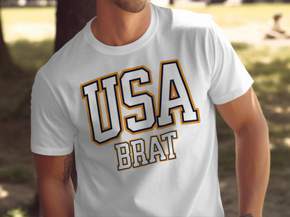 White t-shirt with bold outlining text "USA BRAT" in navy and gold.