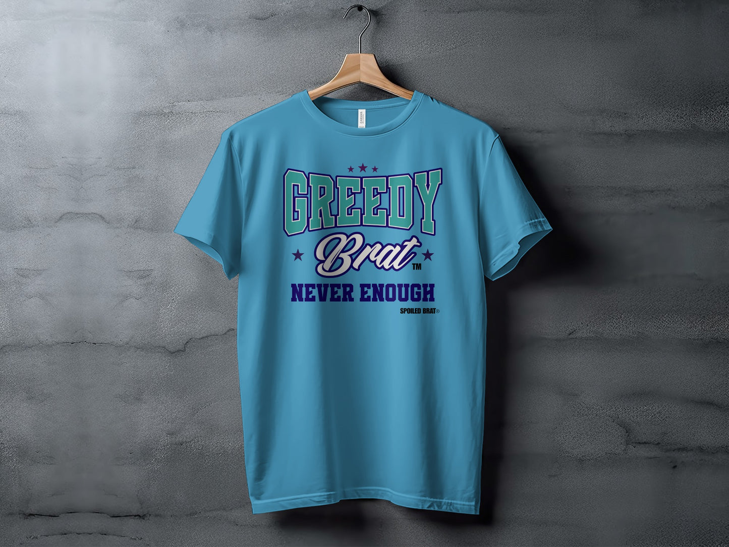 Light blue t-shirt with "GREEDY Brat NEVER ENOUGH" text and stars graphic.