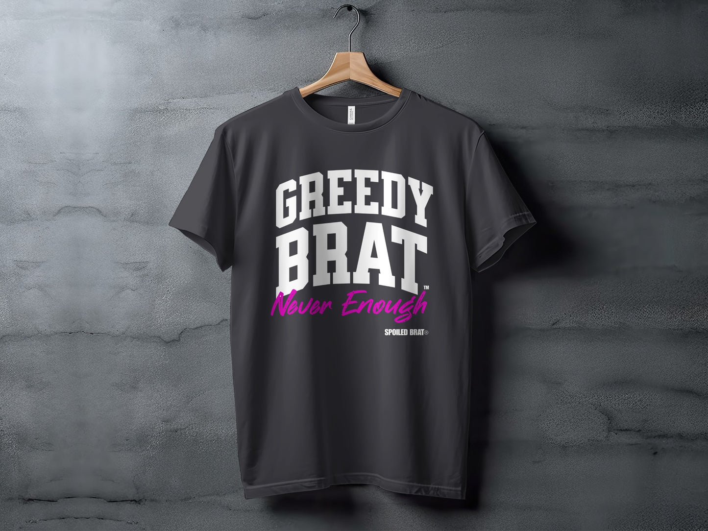 Dark grey t-shirt with "GREEDY BRAT" and "Never Enough" text in white and magenta.