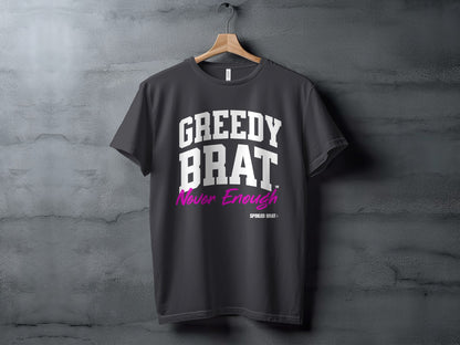 Dark grey t-shirt with "GREEDY BRAT" and "Never Enough" text in white and magenta.
