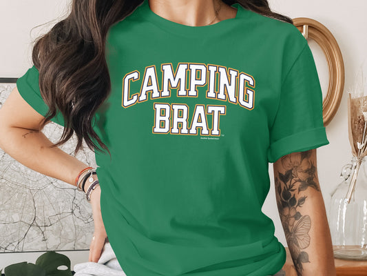 Green t-shirt with white "CAMPING BRAT" text and darker outline.