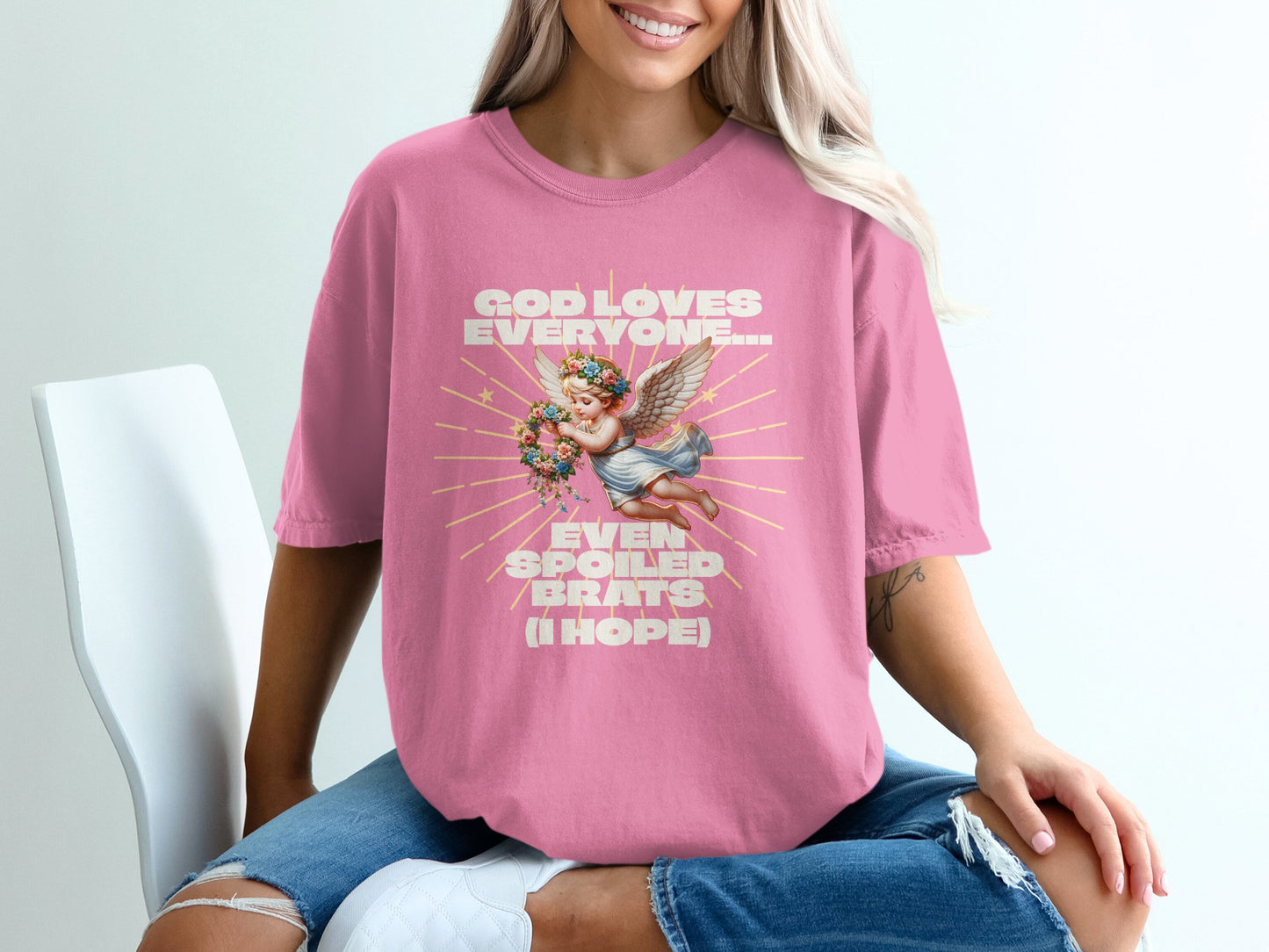 Pink t-shirt with "God loves everyone... even spoiled brats" and cherub design.