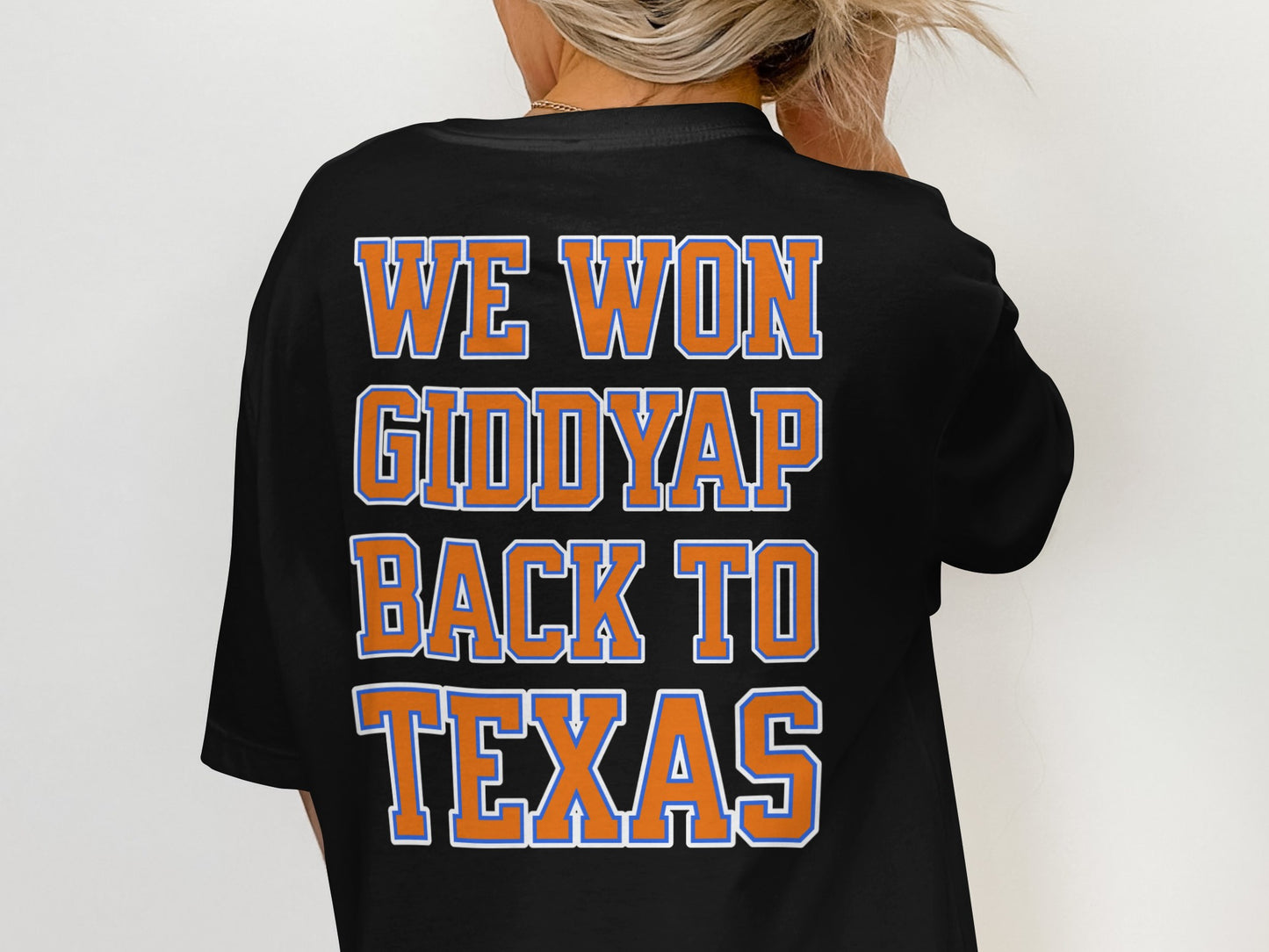 Black t-shirt with orange and blue text reading "WE WON GIDDYUP BACK TO TEXAS".