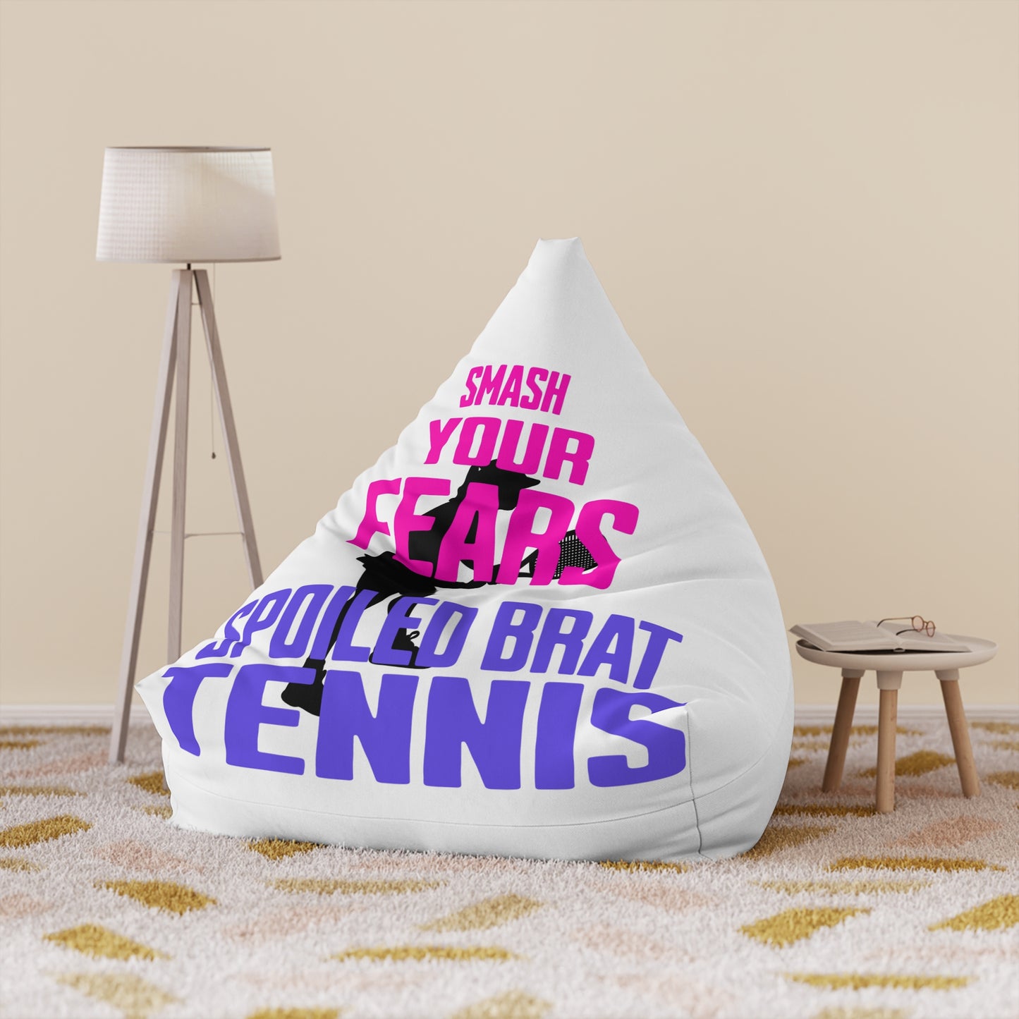 White beanbag chair with pink and purple text reading "SMASH YOUR FEARS SPOILED BRAT TENNIS".