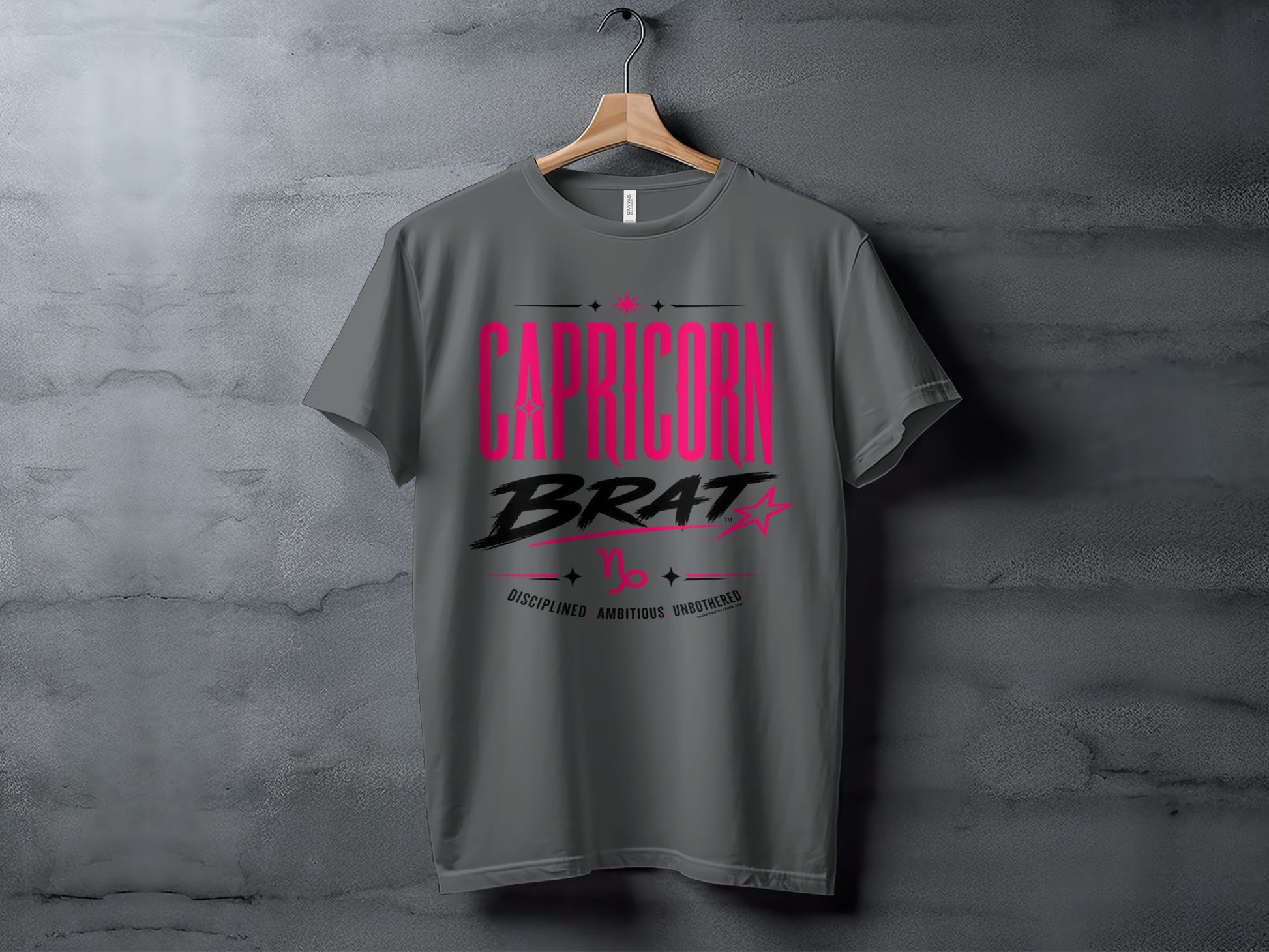 Grey t-shirt with "CAPRICORN BRAT" in pink and black stylized text.