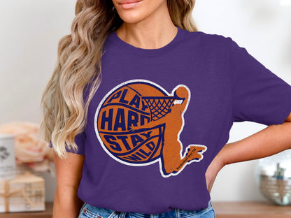 Orange basketball player silhouette with text "PLAY HARD STAY WILD" on purple t-shirt.