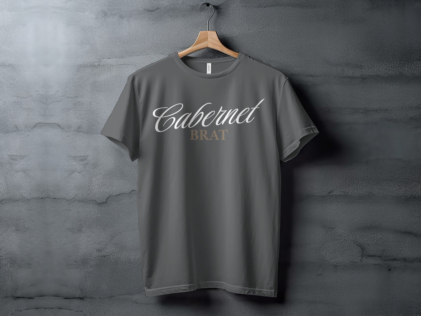 Dark grey t-shirt featuring "Cabernet BRAT" text in white and beige on a wooden hanger.