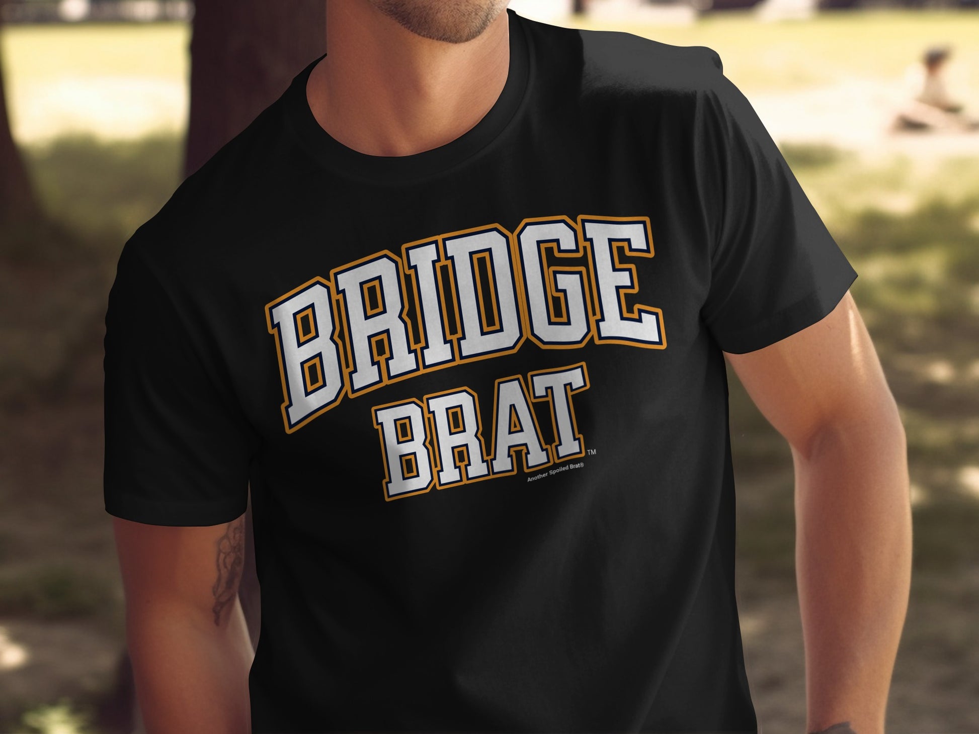 Black t-shirt with white and orange "BRIDGE BRAT" graphic.
