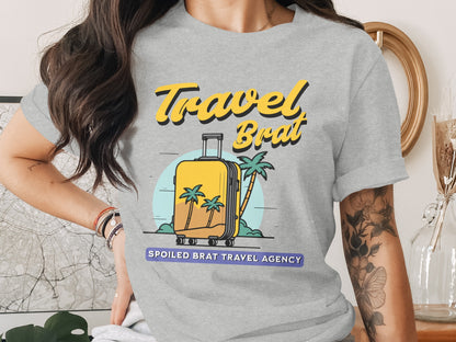 T-shirt graphic with yellow text "Travel Brat" and a suitcase with palm trees.