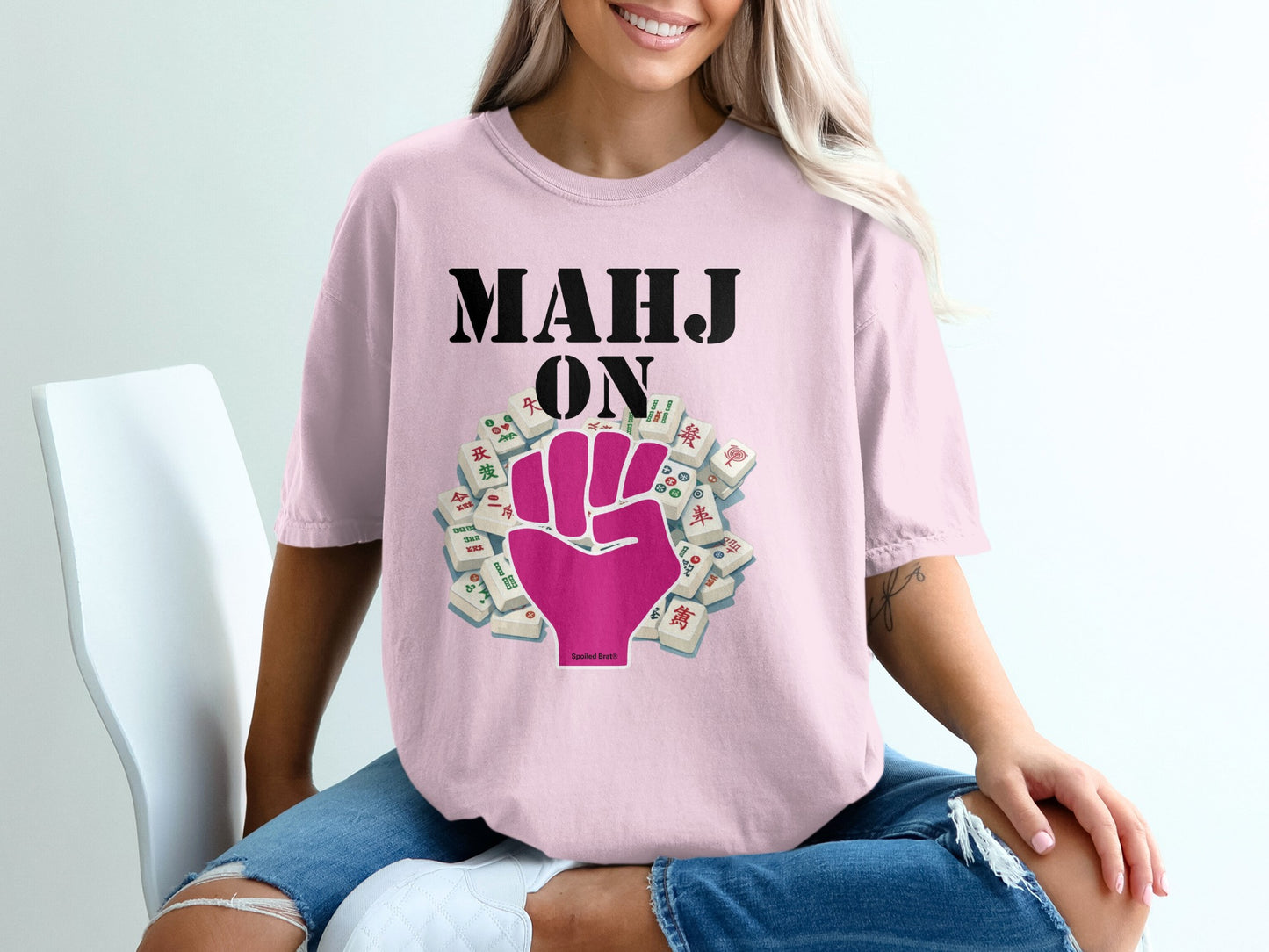 Pink t-shirt with black text "MAHJ ON" and a pink fist surrounded by mahjong tiles.