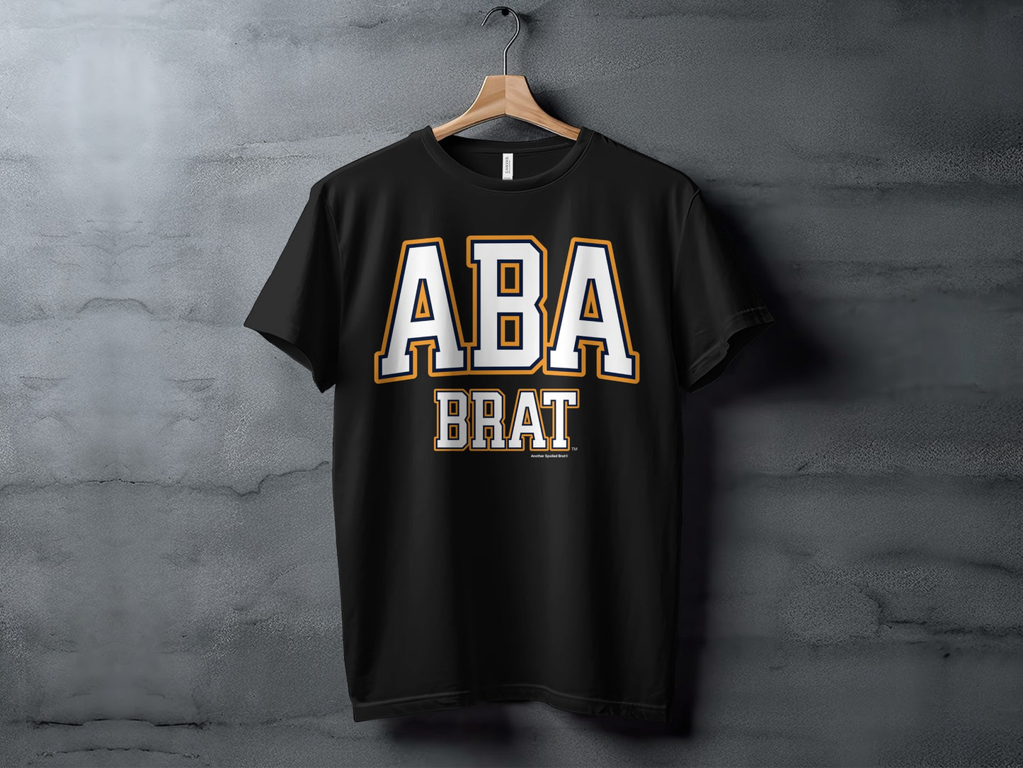 Black t-shirt with "ABA BRAT" text in white and gold collegiate style lettering.