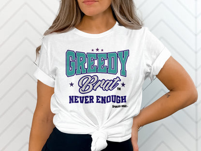 White t-shirt with "GREEDY Brat NEVER ENOUGH" graphic and trademark symbols.