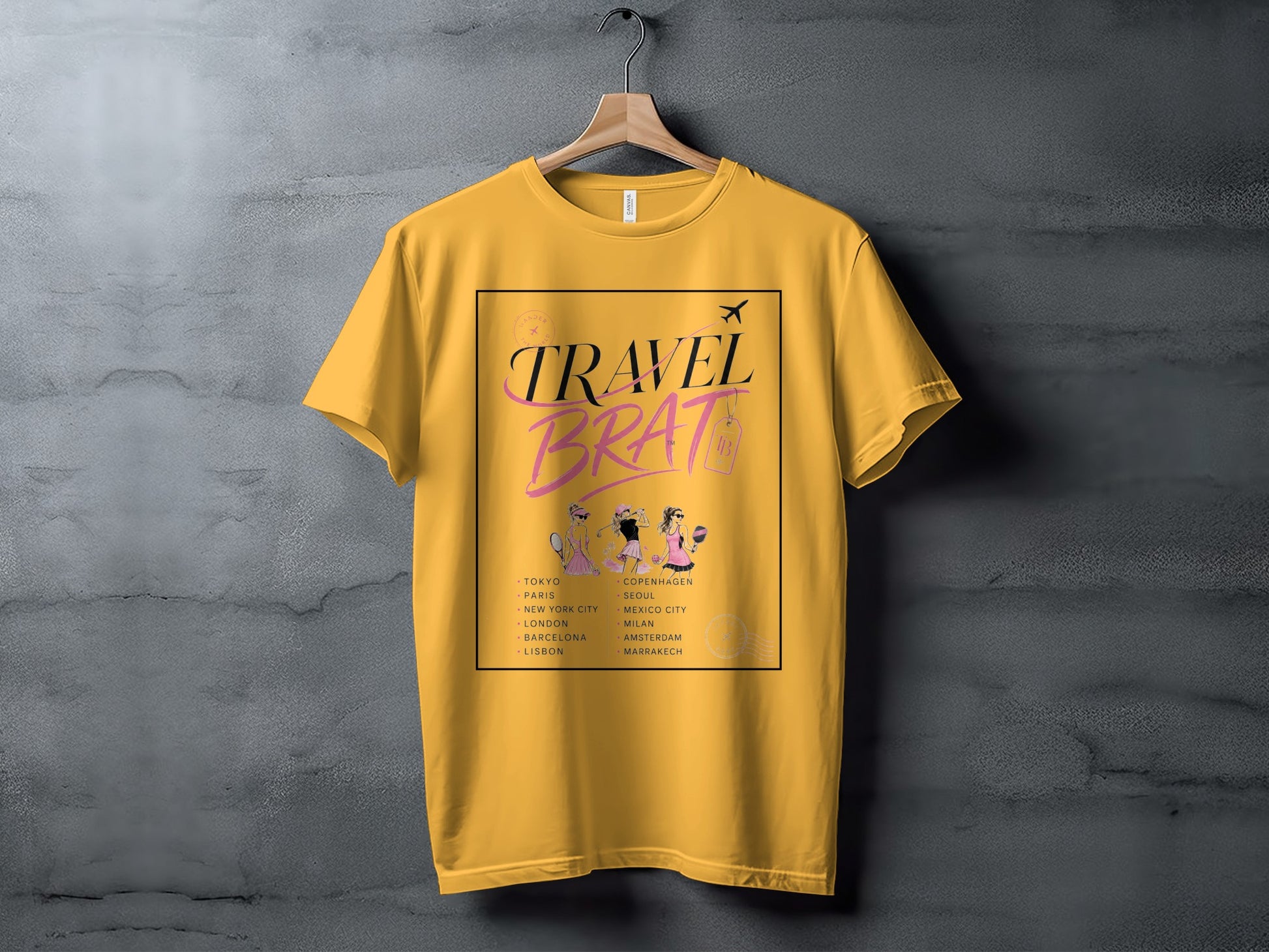 Yellow t-shirt with "TRAVEL BRAT" graphic and list of world cities.