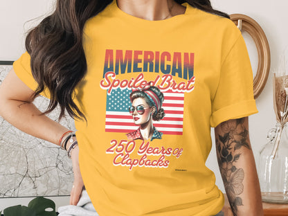 Yellow t-shirt with "AMERICAN SPOILED BRAT 250 Years of Clapbacks" and a retro woman.