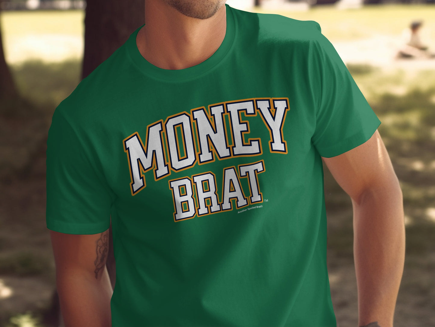 Green t-shirt with "MONEY BRAT" in a varsity-style font.
