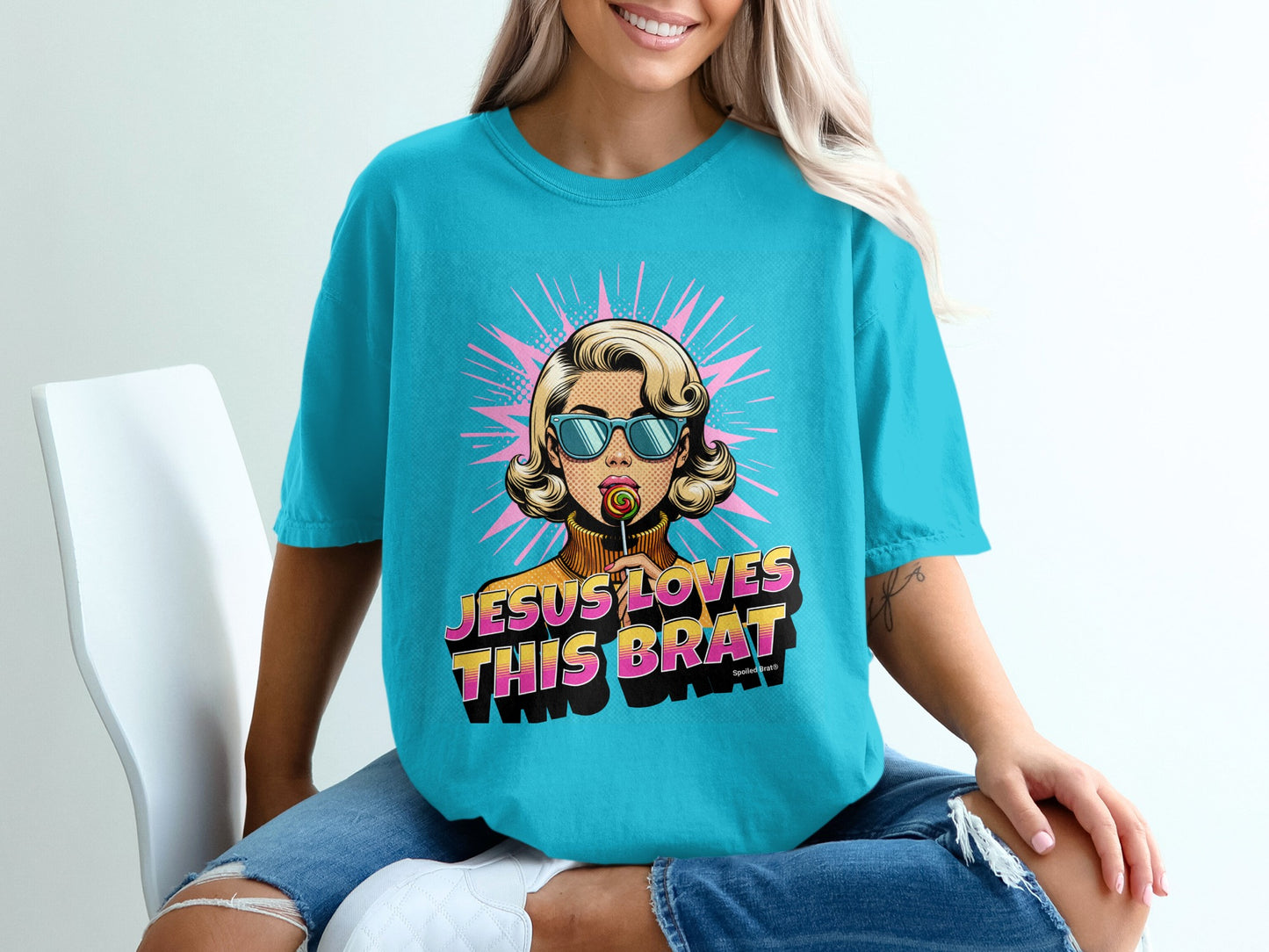 Woman wearing a turquoise t-shirt with pop art design of a woman holding a lollipop.