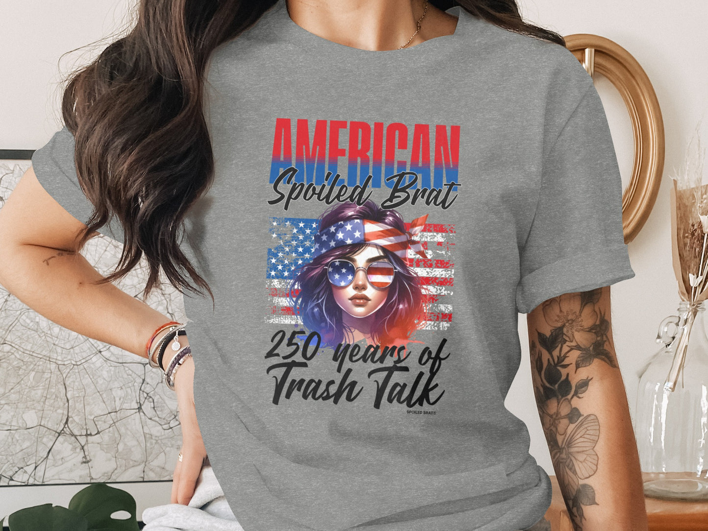 Gray t-shirt with "AMERICAN Spoiled Brat 250 Years of Trash Talk" and US flag graphic.
