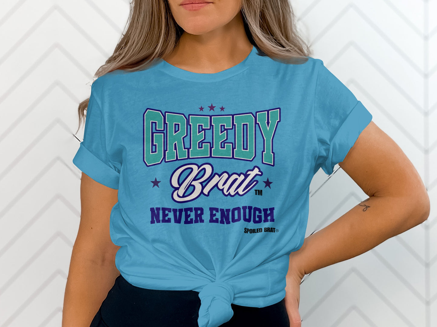 Turquoise t-shirt with text "GREEDY Brat NEVER ENOUGH SPOILED BRAT®".