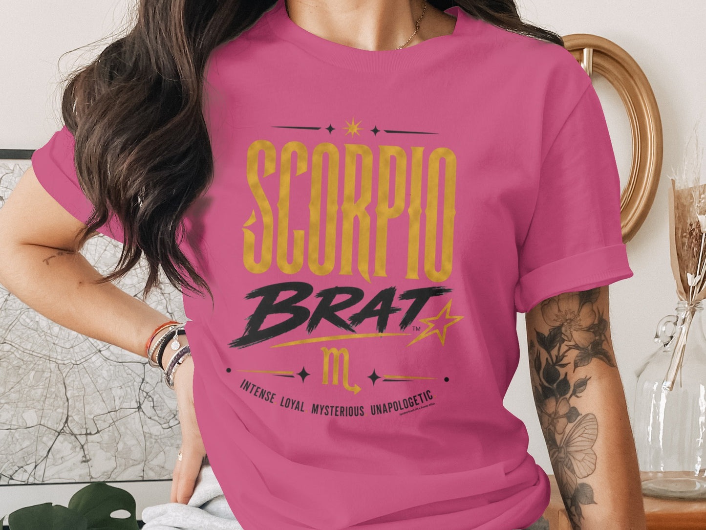 Pink t-shirt with "SCORPIO BRAT" graphic and Scorpio zodiac symbol.