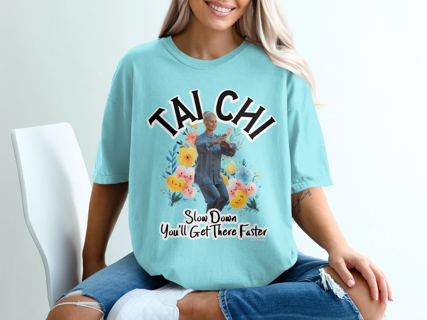 Light blue t-shirt with "Tai Chi" and a woman practicing Tai Chi amongst flowers.