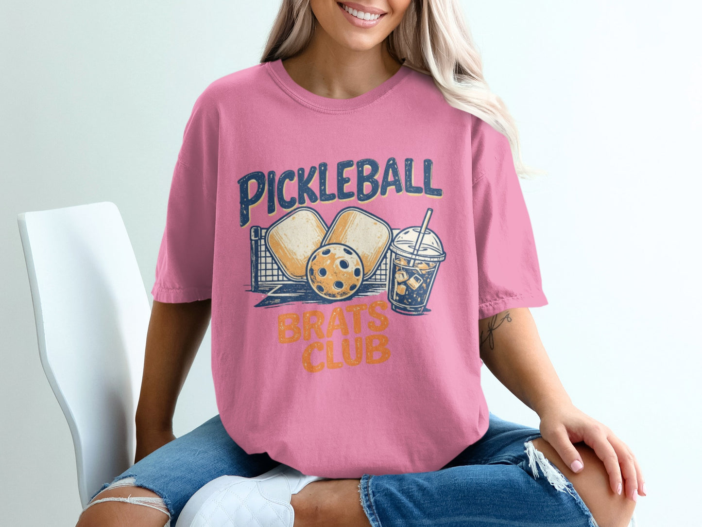 Pink t-shirt with "Pickleball Brats Club" graphic and pickleball gear.