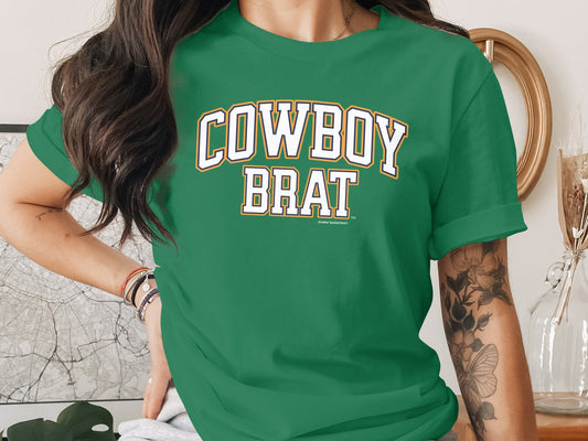 Green t-shirt with "Cowboy Brat" text in white and yellow athletic lettering.