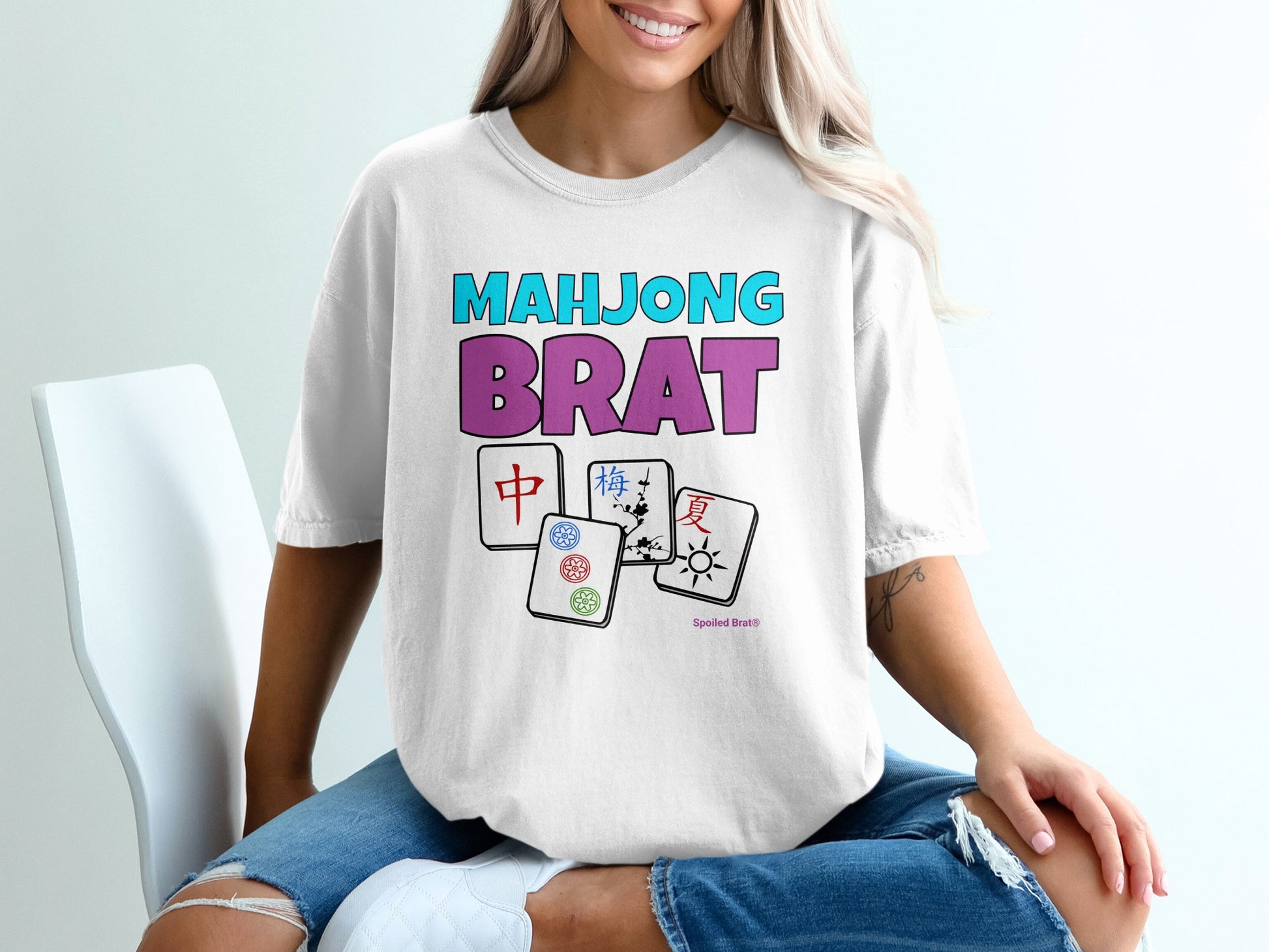 White t-shirt with "Mahjong Brat" text and Mahjong tile graphics.