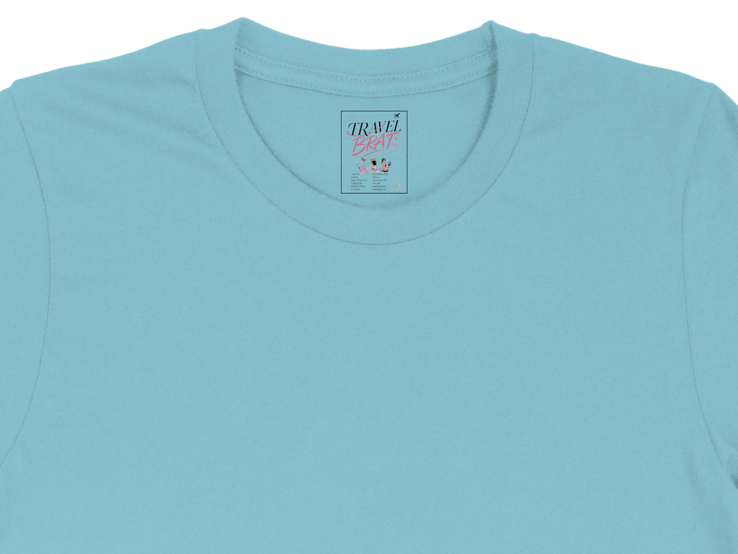 Light blue t-shirt with "TRAVEL BRAT" graphic and city list on the tag.