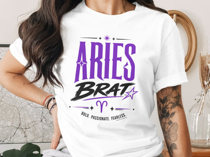 White t-shirt with purple text "Aries Brat" and astrological symbols.