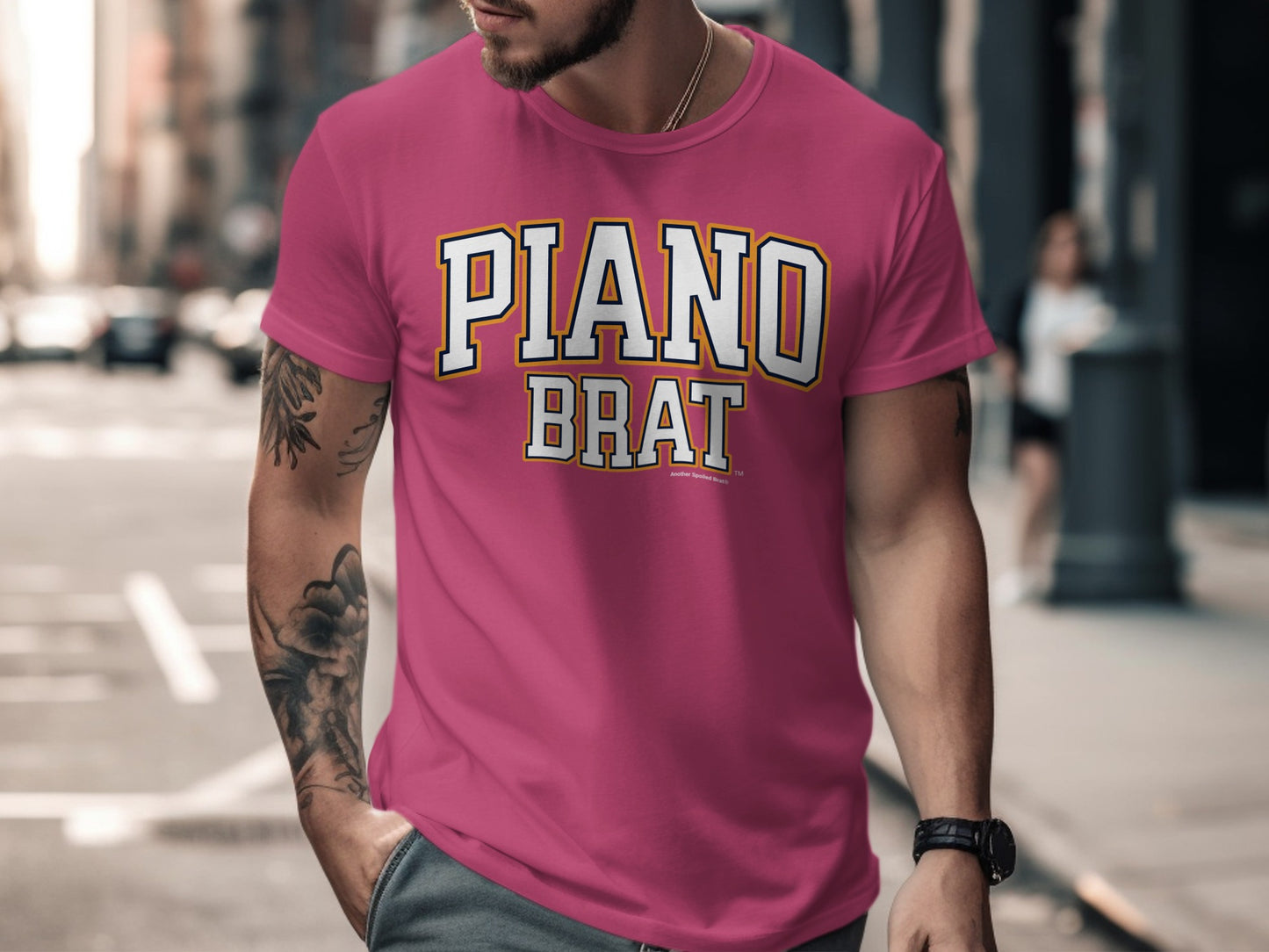 Pink t-shirt with "PIANO BRAT" text and a blurred urban background.
