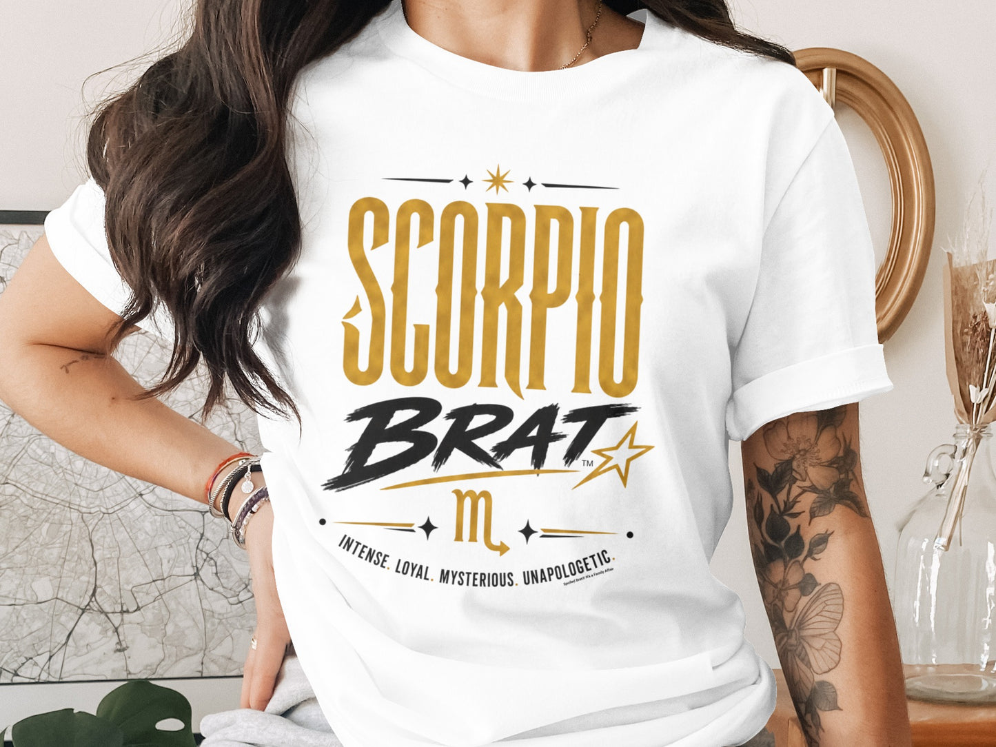 White t-shirt with "SCORPIO BRAT" text, Scorpio symbol, and descriptive words.