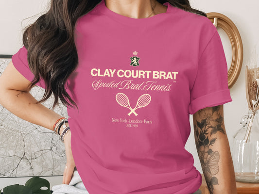 Pink t-shirt with "Clay Court Brat Spoiled Brat Tennis" text and tennis rackets.