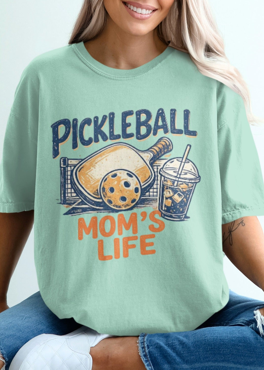 Mint t-shirt with "Pickleball Mom's Life" text, paddle, and drink.