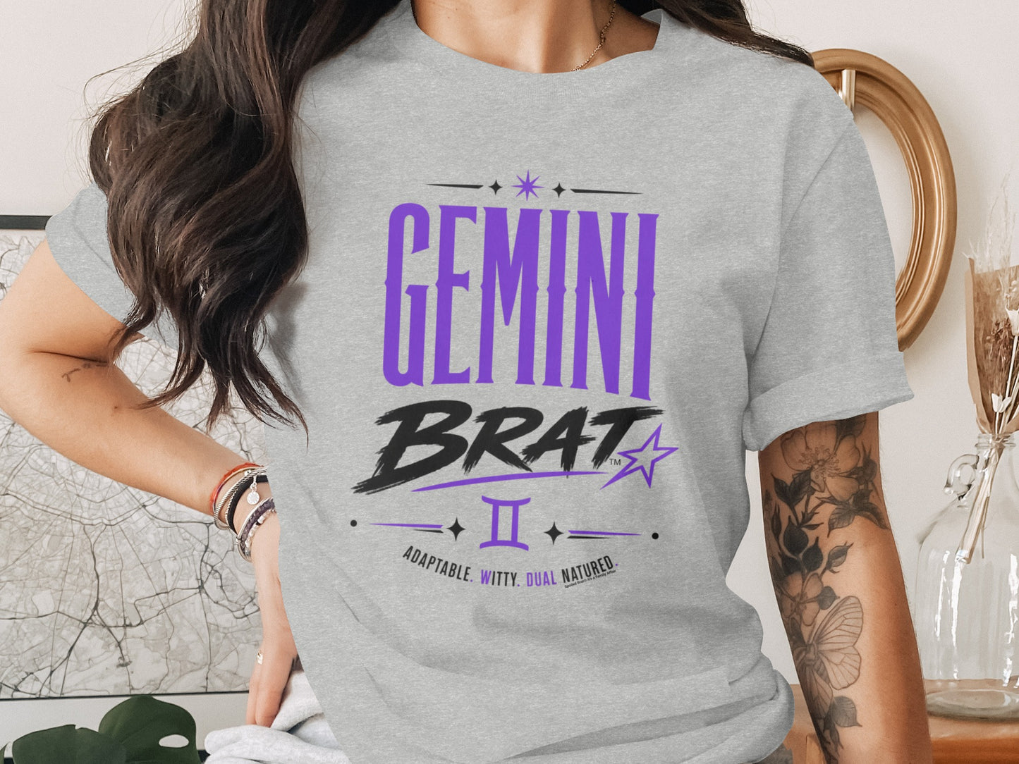 Grey t-shirt with purple "GEMINI BRAT" text, Gemini symbol, and descriptive words.