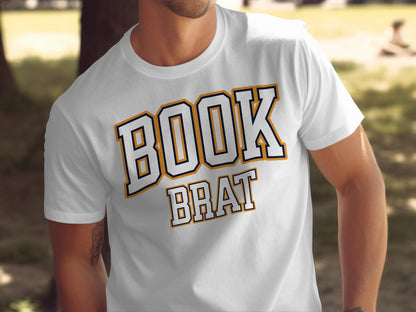 White t-shirt with "BOOK BRAT" text in blue and gold collegiate lettering.