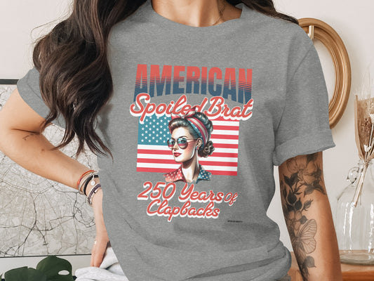 Grey t-shirt with "American Spoiled Brat 250 Years of Clapbacks" and American flag graphic.