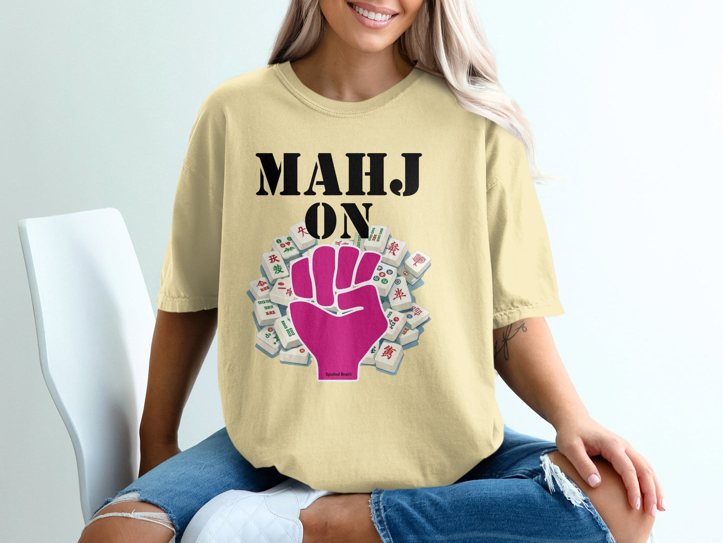 Mahjong tiles and fist graphic on yellow t-shirt worn by a woman.