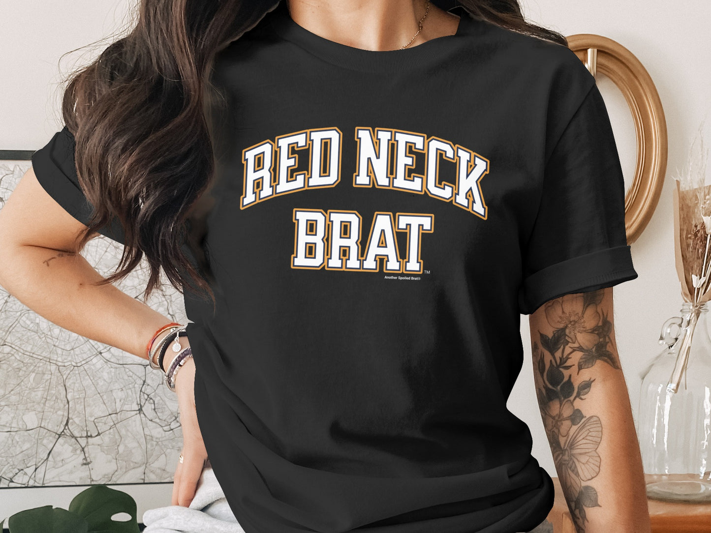 Black t-shirt with "RED NECK BRAT" text in white with yellow and blue trim.