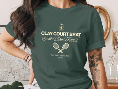 Green t-shirt with "CLAY COURT BRAT Spoiled Brat Tennis" text and crossed tennis rackets.