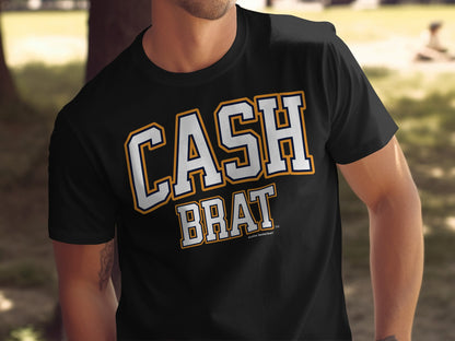Black t-shirt with "CASH BRAT" text in white and orange collegiate style lettering.